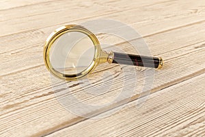 A magnifying glass on a wooden table. The concept of information search. Selective focus