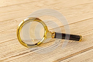 A magnifying glass on a wooden table. The concept of information search. Selective focus