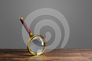 Magnifying glass on a wooden table. Search and analysis, analytics and study. Pay attention to details and problems