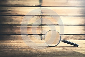 Magnifying glass on wooden table. Search and discover