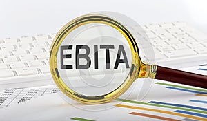 Magnifying glass with the word EBITA on chart background