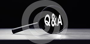Magnifying glass with the word Q and A - question and answer on table