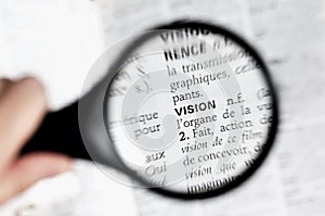 Magnifying glass on the word vison in a dictionary photo