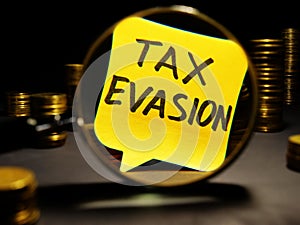Magnifying glass and words tax evasion with money photo
