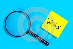 Magnifying loupe and a sticker with the word work on a blue background.