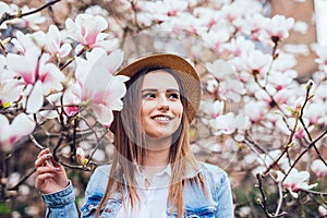 Magnolia. girl or cute woman near blossoming, magnolia flowers tree in spring park on spring sunny day