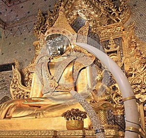 Mahamuni Buddha golden statue, carved ivory tusks in foreground in Mawlamyine, Myanmar