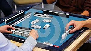 A mahjong table with an active game and the hands of the participants in the game.