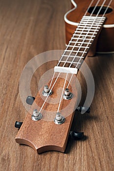 Mahogany soprano ukulele resting on wooden table, vertical orientation