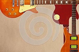 Mahogany and sunburst electric guitars and and back of guitar body on rough cardboard background, with plenty of copy space.