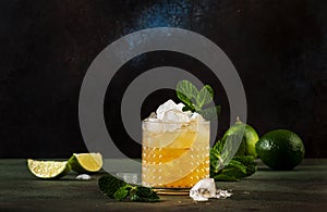 Mai Tai trendy alcoholic cocktail with rum, liqueur, syrup, lime juice, mint and crushed ice. Dark background, bar tools, copy