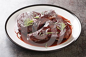 Maiale ubriaco is a traditional Tuscan dish simmered pork chops with red wine closeup on the plate. Horizontal photo