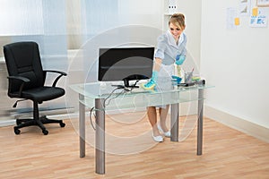 Maid cleaning desk in office