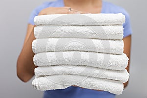 Maid holding a stack of white fresh towels