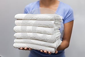 Maid holding a stack of white towels