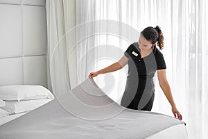Maid making bed in hotel room. Housekeeper Making Bed