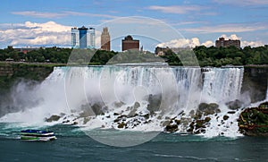 Maid of the mist cruise tour boat passing American Falls in the waters of Niagara Falls