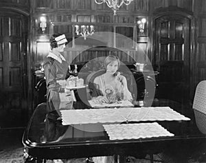 Maid serving woman at table