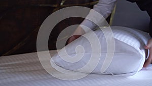 Maid straightens a pillow in a small, cozy hotel room.