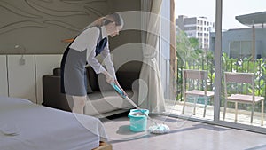 Maid was cleaning the floor with a mop in a hotel room