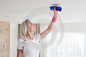 Maid woman holding mop pile, cleaning ceiling in living room. House cleaning service concept.