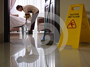 Maid at work and cleaning in luxury hotel room