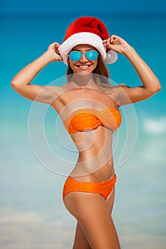 Maiden in orange bikini and hat of Santa Claus