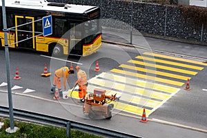 Maienfeld, GR / Switzerland - April 2, 2019: workers painting and marking a pedestrian crosswalk with fresh yellow paint to ensure