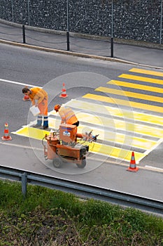 Maienfeld, GR / Switzerland - April 2, 2019: workers painting and marking a pedestrian crosswalk with fresh yellow paint to ensure