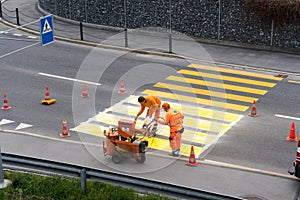 Maienfeld, GR / Switzerland - April 2, 2019: workers painting and marking a pedestrian crosswalk with fresh yellow paint to ensure