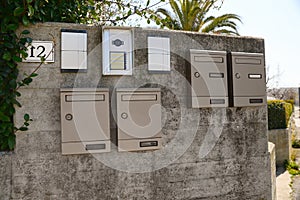 Mail boxes and intercoms on grey concrete wall outdoors