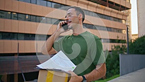 Mail courier talking smartphone delivering package modern neighbourhood closeup