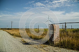 Mailbox near a village road on the background of a field with a wind farm