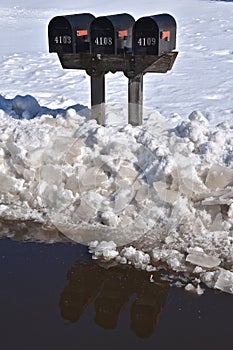 Mailboxes casts reflections on water from snow melt