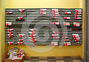 Mailboxes in the entrance hall of a residential house filled with paper flyers. Russia