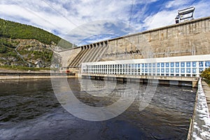 The main building with turbines of the Zeya hydroelectric station on the background of a concrete dam.