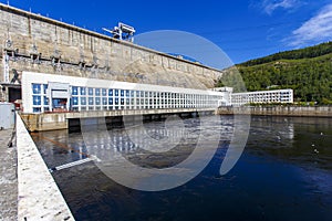 The main building with turbines of the Zeya hydroelectric station on the background of a concrete dam.