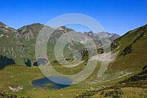 Main Caucasian Ridge and mountain lake surrounded with alpine meadows