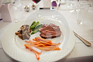 Main course menu with beef, carrots, beans and mushrooms freshly served on a white plate.