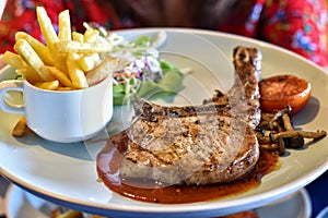 Main course pork t-bone steak with vegetables salad in white dish. photo