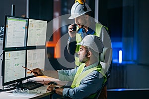 Main engineer and workers operator wearing safety vests and hard hats control product process on factory uses SCADA system