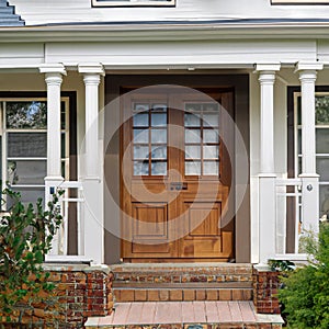 Main entrance door in house. Wooden front door with gabled porch and landing. Exterior of georgian style home cottage with white