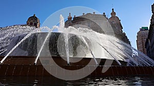 Main fountain with splashes of water in Ferrari Square against backdrop of beautiful architecture of city. Piazza de