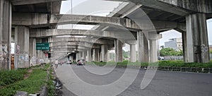 A main highway under a connecting toll road and several vehicles passing by