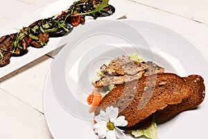 Main meal with bread on white wood background.