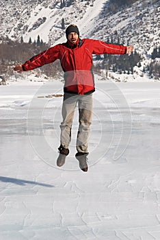 Main in red jumping on winter lake