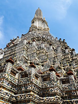 The main spire at the Wat Arun Temple, the Temple of Dawn, with its intricite facade of color is stretching towards a blue sky in