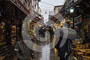 Main street of Kadikoy market, on the Asian side of the city, with restaurants around, crowded, during a snow storm in winter