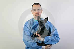 The main subject is out of focus, male surgeon veterinarian hold small black dog