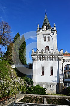 Hlavní věž neoklasicistního zámku Amrozy na západním Slovensku se záhony rostlin a kvetoucími keři před zámkem. S